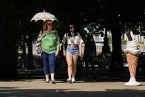 Žena se chrání deštníkem před slunečními paprsky na břehu řeky Temže v Londýně 18. července 2022
