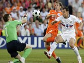 Ruský brankář Igor Akinfejev chytá míč před dotírajícím Nizozemcem Rafaelem van der Vaartem, asistuje mu obránce Sergej Ignaševič.