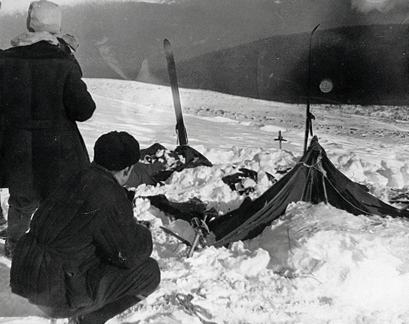 Sněhem zavalený stan Ďatlovovy výpravy, k němuž pátrači dorazili až 26. února. Stan byl rozříznut zevnitř, skupina před něčím utíkala. Vlevo od stanu pátrači Vladislav Karelin (stojící) a Jurij Koptelov