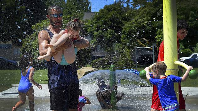 Lidé ve městě Olympia se ochlazují ve fontáně v parku během horkého dne
