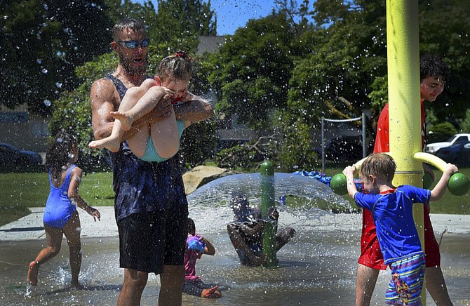 Lidé ve městě Olympia se ochlazují ve fontáně v parku během horkého dne