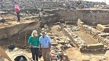 Badatelé zkoumají ruiny starověkého města, přičemž uprostřed odhalených zdí nacházejí stopy dávné destrukce
