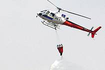Vrtulník z vaku vypouští vodu na hořící křoviska v kopcích ostrova Gran Canaria.