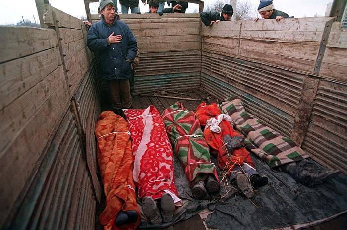Čečeni se dívají na mrtvá těla zabalená do přikrývek na korbě náklaďáku během bitvy o Groznyj, leden 1995