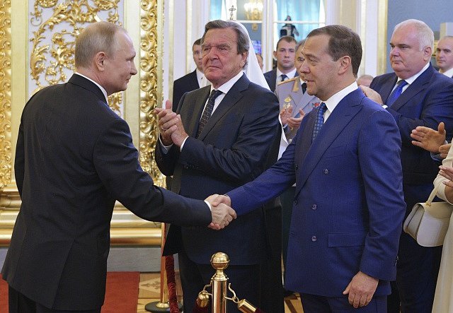 Vladimiru Putinovi přeje Dmitrij Medveděv. Uprostřed bývalý německý kancléř Gerhard Schröder.