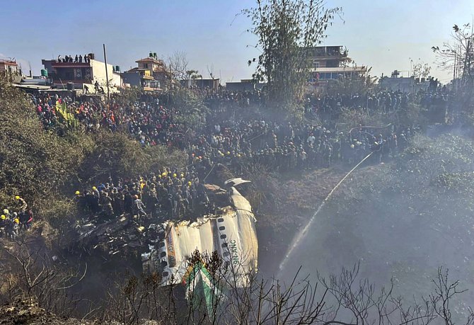 Místní obyvatelé sledují trosky letadla, které se zřítilo poblíž mezinárodního letiště Pokhara v Nepálu
