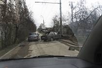 Řidič v Mariupolu se vyhýbá havarovanému vozu ve snaze uniknout ruskému bombardování