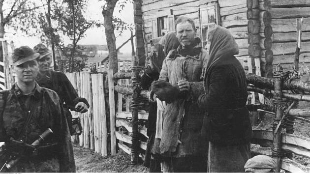 Vojáci Waffen-SS v dobyté a obsazené sovětské vesnici. Obyvatelé jsou vidět, jak stojí před domy.