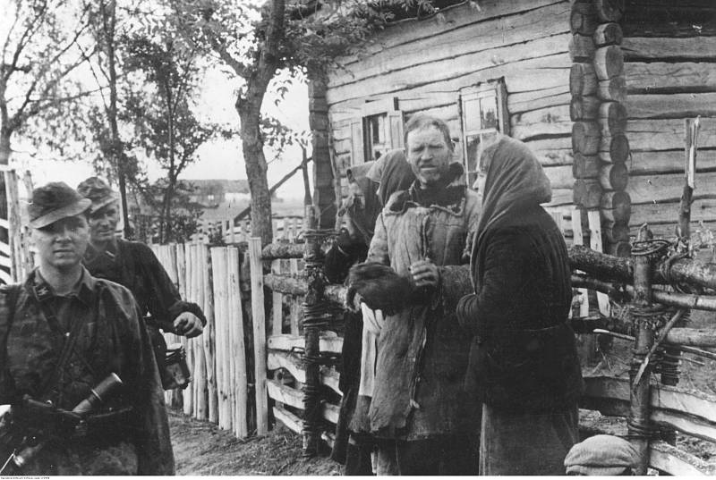 Vojáci Waffen-SS v dobyté a obsazené sovětské vesnici. Vesničané stojí před domy