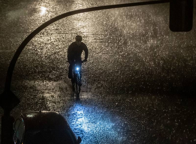 Cyklista během bouřky - Cyklista jede ulicí během noční bouřky.