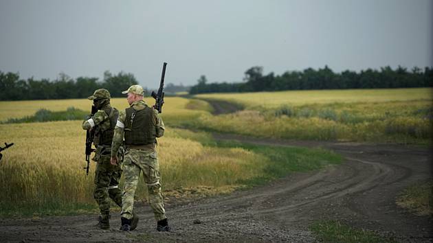 Ruští vojáci hlídkují u pole s pšenicí v Záporoží 14. června 2022