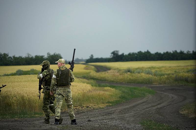 Ruští vojáci hlídkují u pole s pšenicí v Záporoží 14. června 2022