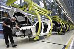 Zaměstnanec automobilky Mercedes-Benz pracuje s ochrannou rouškou na montážní lince