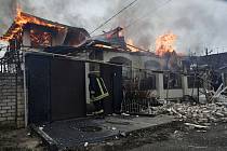 Hasič stojí u domu v ukrajinském Chersonu, který hoří po ruském ostřelování 6. ledna 2023