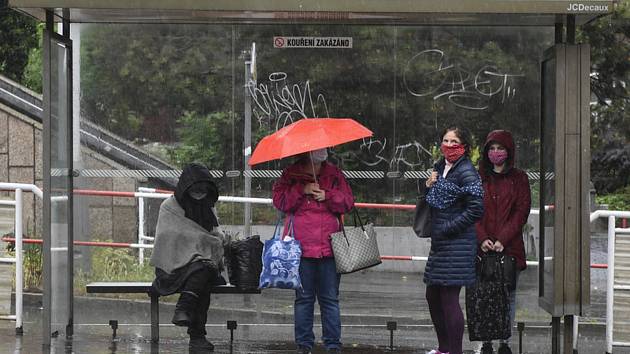 Lidé se kryjí na zastávce před deštěm 11. května 2020 v Praze