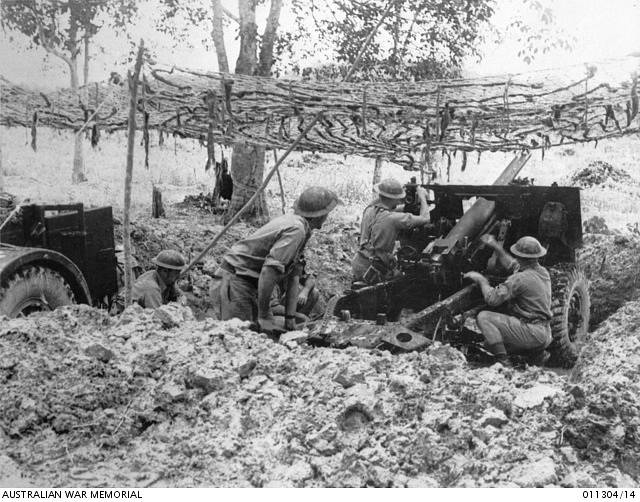 Posádka 25liberního protitankového děla 8. australské divize, AIF, se pod maskovací sítí připravuje zahájit palbu na blížící se Japonce