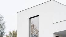 Kompaktní bílé hmotě vily dominuje vysoké okno do převýšeného obývacího prostoru