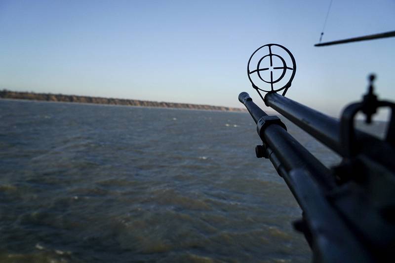 Vrtulník s namířeným kulometem monitoruje situaci nad částí moře.