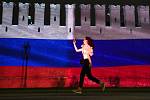 Žena v Moskvě prochází  kolem zdi Kremlu nasvícené v ruských státních barvách, 13. června 2020