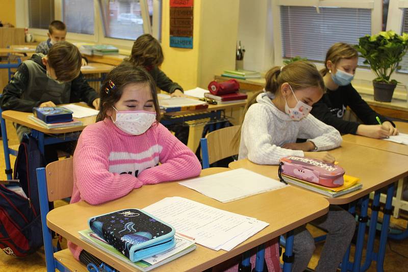 Výuka na první stupni v době koronaviru? Žáci sedí v rouškách a na třetí ze čtyř vyučovacích hodin se celá třída chodí ven provětrat.