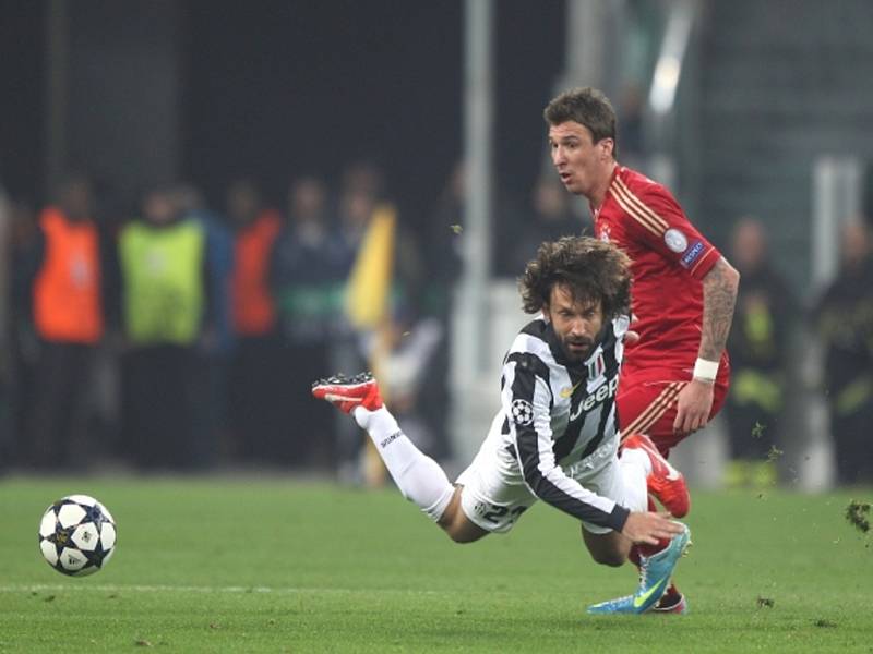 Andrea Pirlo z Juventusu Turín (vlevo) plachtí po kontaktu s Mariem Mandzukičem z Bayernu Mnichov.