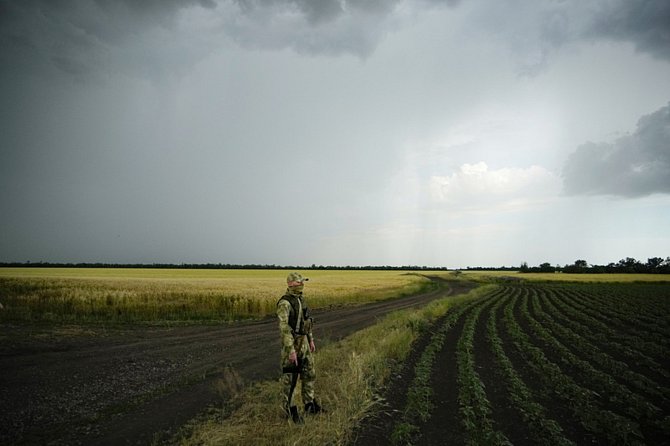 Ruský voják hlídkuje u pole s pšenicí v Záporoží 14. června 2022