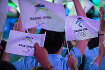 Účastníci mávají 17. září 2021 s vlaječkami s logy zimních olympijských her a paralympiády v Pekingu 2022.