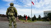 Mladý pár prochází kolem ruského vojáka střežícího centrum Chersonu za ruské okupace