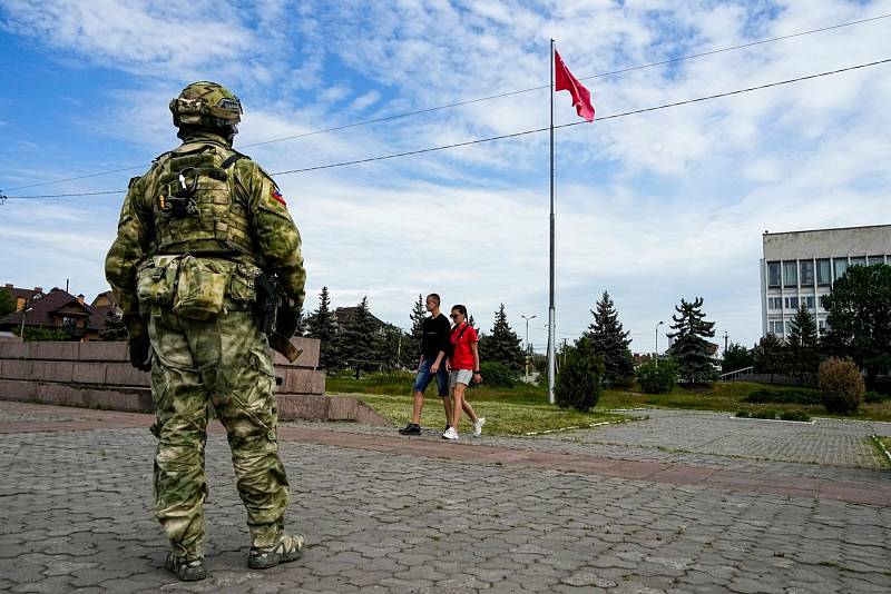 Mladý pár prochází kolem ruského vojáka střežícího centrum Chersonu za ruské okupace