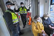 Příslušníci městské policie dohlížejí 25. února 2021 v tramvaji pražské MHD na dodržování nově zavedené povinnosti nosit na frekventovaných místech respirátor