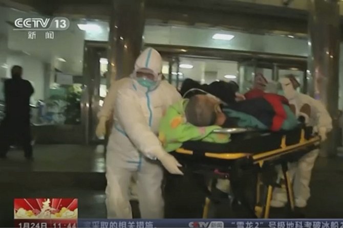 Zdravotníci v ochranných oblecích transportují pacienta do nemocnice ve městě Wu-chan