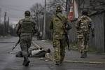 Ukrajinští vojáci po osvobození města Buča, před nimi mrtvý na silnici.