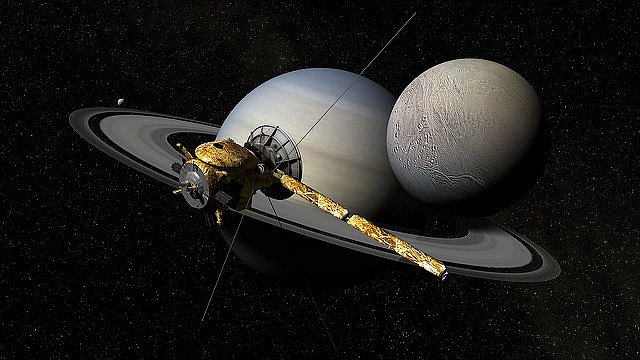 Sonda Cassini, v pozadí měsíc Enceladus
