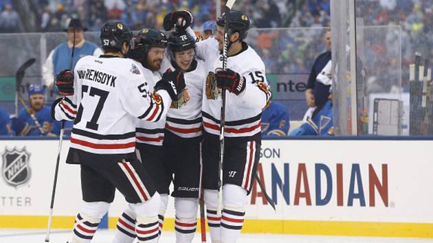 Michal Kempný (druhý zleva) se raduje se spoluhráči z Chicaga z gólu v duelu NHL pod širým nebem.