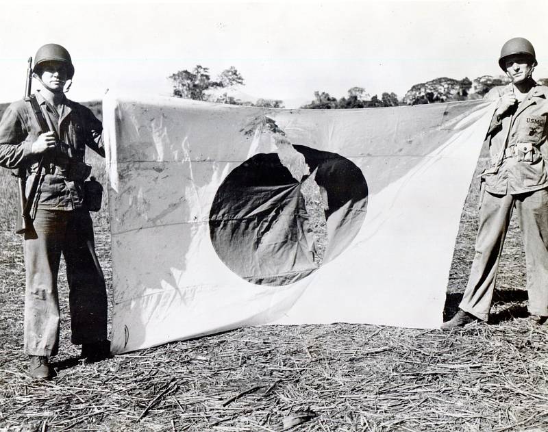 Američtí vojáci pózují s ukořistěnou japonskou vlajkou na letišti ostrova Guadalcanal