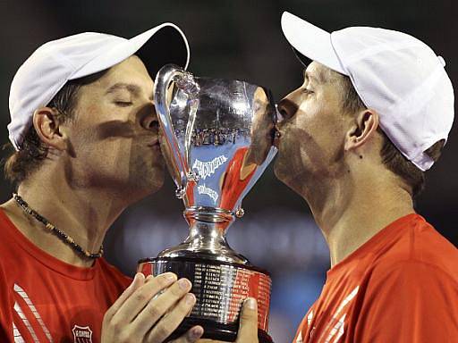 Bratři Bob (vlevo) a Mike Bryanové líbají pohár pro šampiony čtyřhry na Australian Open. 