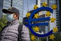 Muž v roušce prochází kolem znaku eura před sídlem Evropské centrální banky ve Frankfurtu nad Mohanem, 5. května 2020.
