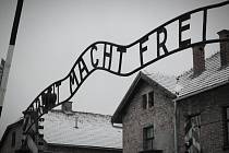 Osvětim. Vstupní brána do tábora s nápisem „Arbeit macht frei“, který byl umístěn na branách mnoha nacistických koncentračních táborů jako cynické prohlášení, že sebeobětování otrockou prací může přinést duševní svobodu.