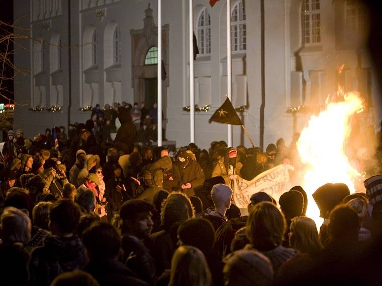 Protivládní demonstranti obklopují vatru před Národním divadlem v islandském Reykjavíku. 