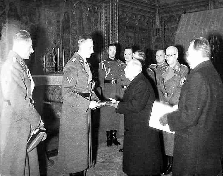 Protektorátní prezident Emil Hácha předává zastupujícímu říšskému protektorovi Reinhardu Heydrichovi klíče od Korunní komory, vlevo přihlíží Karl Hermann Frank