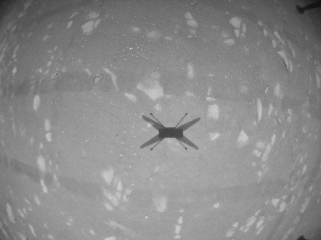 Stín helikoptéry Ingenuity na povrchu Marsu při jejím třetím letu nad planetou.