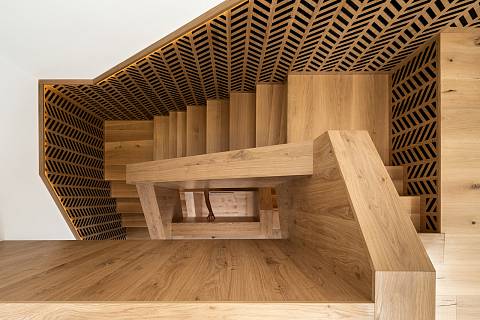 Masivní dřevěné schodiště patří mezi dominanty domu. Částečně zasahuje i do nosné stěny.