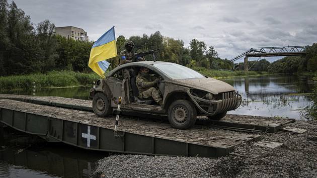 Členové ukrajinských výsadkových vojsk v autě s vlajkou na pontonovém mostu na cestě přes řeku Severní Doněc v oblasti Izjumu 14. září 2022