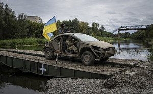 Členové ukrajinských výsadkových vojsk v autě s vlajkou na pontonovém mostu na cestě přes řeku Severní Doněc v oblasti Izjumu 14. září 2022