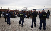 Maďarští policisté dohlíží na migranty čekající na vlak do Srbska.
