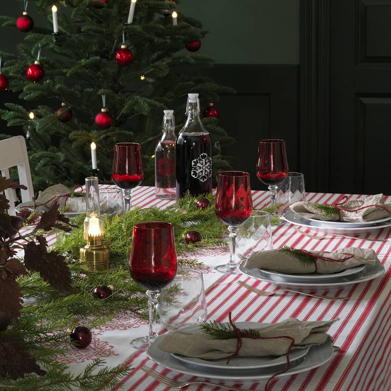 Různé způsoby výzdoby svátečního stolu v typických barvách Vánoc – červené sklenice, zelené jehličí.