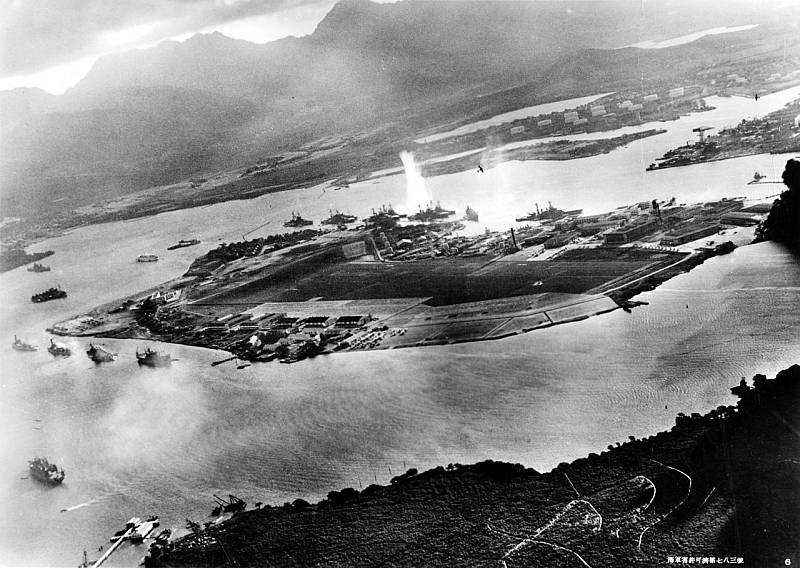 Fotografie pořízená z japonského letadla během torpédového útoku na lodě kotvící po obou stranách Fordova ostrova krátce po zahájení útoku na Pearl Harbor. Pohled k východu se zásobovacím skladem, ponorkovou základnou a skladem paliva