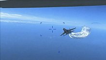Ruská stíhačka Su-27 se přibližuje k zadní části dronu MQ-9 Reaper a začíná vypouštět palivo na fotografii z videa amerického ministerstva obrany 16. března 2023