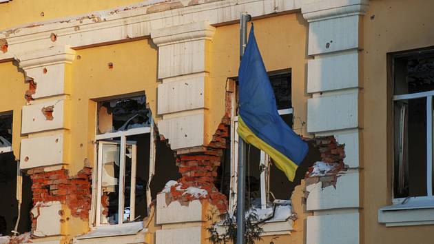 Ukrajinská vlajka na budově poškozené ruským bombardováním.