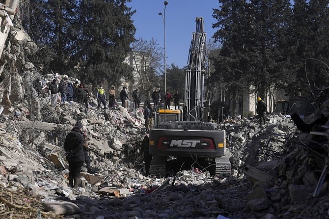 Bagr odstraňuje trosky zničené budovy po zemětřesení v tureckém Kahramanmarasu, 13. února 2023